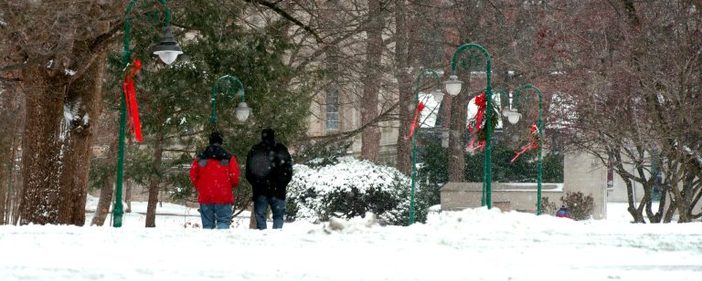   Two people walk through the snow on the Indiana University campus Friday, Dec. 21, 2012 in Bloomington, Ind. The area received about an inch of snow with howling winds through the night. (AP Photo, Bloomington Herald-Times, David Snodgress)  