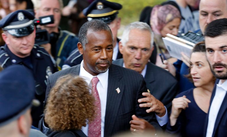 Republican presidential candidate and retired neurosurgeon Ben Carson is escorted as he walks through a crowd of students during a campaign stop at the University of New Hampshire Wednesday, Sept. 30, 2015, in Durham, N.H. (AP Photo/Jim Cole)