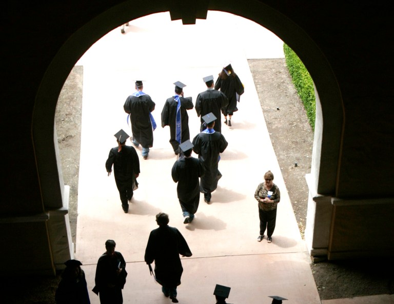 Grads with diplomas exit through the tunnel between the racetrack and the saddling area after Commencement ceremonies at California State University-San Marcos, in Del Mar, Calif. (Jim Baird / San Diego Union-Tribune via AP)