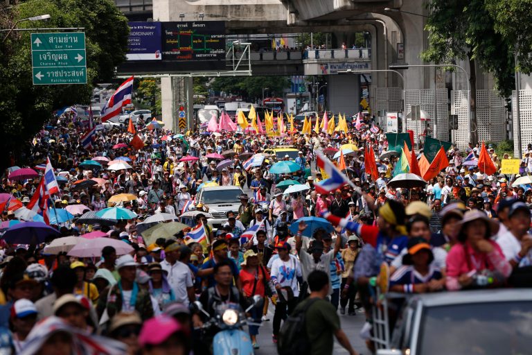Anti-government protesters march through a main road in downtown Bangkok, Thailand, Friday, May 9, 2014. Thailand's anti-graft commission indicted ousted Prime Minister Yingluck Shinawatra on Thursday on charges of dereliction of duty in overseeing a widely criticized rice subsidy program, a day after a court forced her from office. Yingluck was accused of allowing the rice program, a flagship policy of her administration, to proceed despite advice that it was potentially wasteful and prone to corruption. (AP Photo/Vincent Thian)