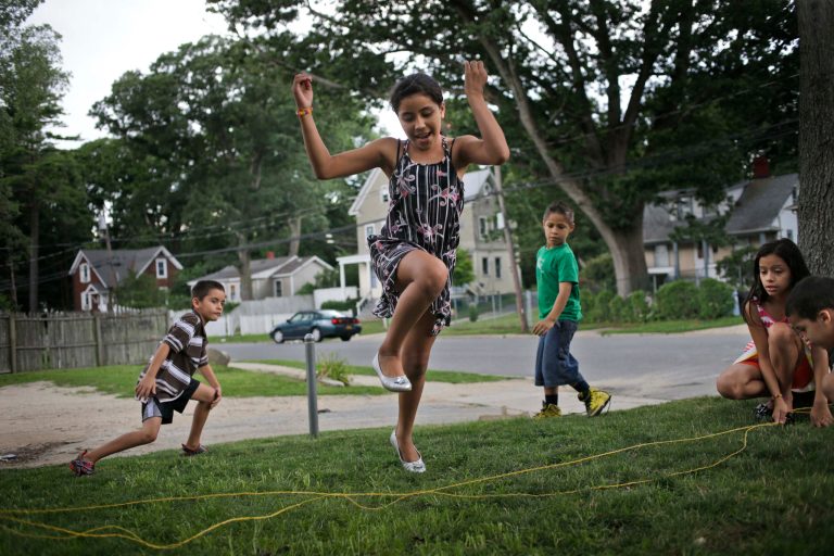 In this July 17, 2014 photo, Maria Ruiz, 9, plays with neighbors in the front yard of her apartment building in Huntington Station, N.Y. Ruiz traveled from Nicaragua to the United States with her sister in June of 2013. Since October 2013, 4,244 minors who crossed Rio Grande River illegally, without their parents, have made New York their home. Metropolitan New York cases are being handled by the federal Immigration Court in New York City, which is struggling to allocate resources, including pro bono lawyers. (AP Photo/Seth Wenig)