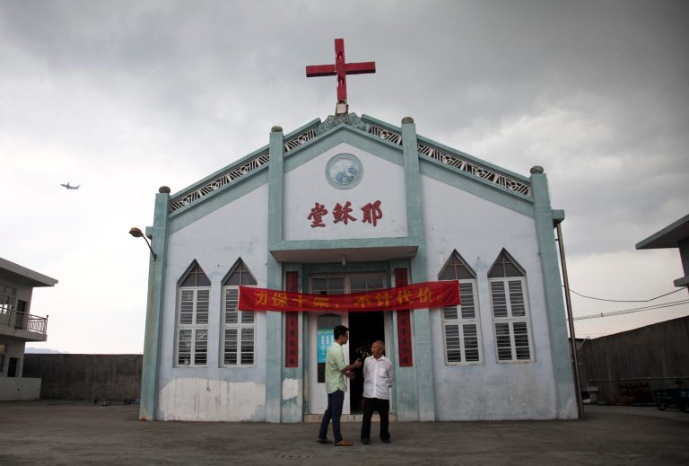 In this photo taken July 15, 2014, Pastor Tao Chongyin, left, speaks with church member Fan Liang'an in front of the Wuxi Christian Church with the words 