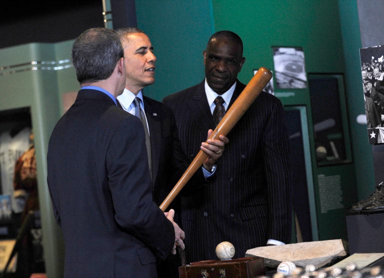 President Barack Obama, accompanied by Baseball Hall of Fame President Jeff Idelson,left, and hall of fame member Andre Dawson, inducted in 2010, holds up Babe Ruth's bat during a tour the Baseball Hall of Fame in Cooperstown, N.Y., Thursday, May 22, 2014. Obama visited the museum to highlight tourism and steps to help spur international visits to the 50 states. Obama said the overall U.S. economy and local businesses will benefit if it isn't a hassle for people from other countries to visit the U.S. and spend money at its hotels, restaurants, tourist destinations and other businesses. (AP Photo/Susan Walsh)