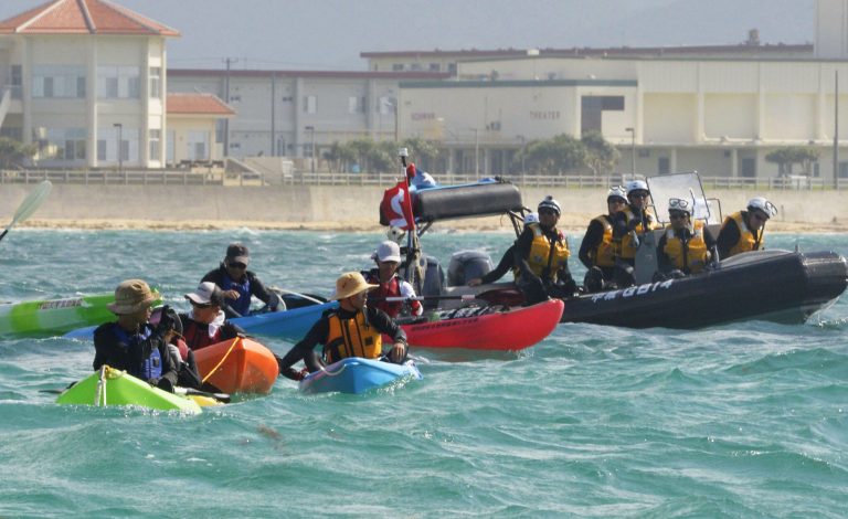 Anti US base protesters in canoe are blocked by a Japan Coast Guard speed boat in Nago, Okinawa, southern Japan, Thursday, Aug. 14, 2014. Japanese officials said buoys are being floated off the southernmost island of Okinawa in one of the first steps in the relocation of an American military base. The buoys define the area where the construction will begin on a facility in coastal Henoko that will house the Marine Corps Air Station Futenma, which will be relocated from a crowded residential area of Okinawa. (AP Photo/Kyodo News) JAPAN OUT