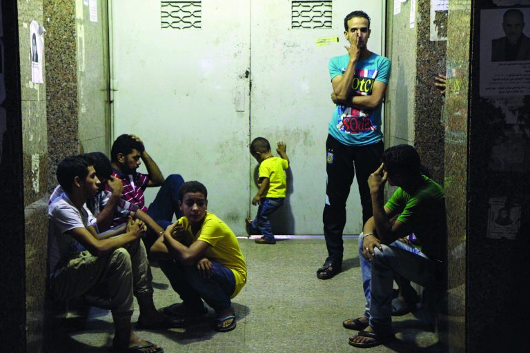 In this Friday Sept. 14, 2012 photo, family members of Ismail Rashad, 36, wait for his body to be released outside the door to the Zenhoum morgue in Cairo, Egypt. His family and doctors at a Cairo hospital said Rashad died yesterday from wounds from rubber bullets in clashes Friday that brought the first Egyptian to be killed in Tahrir Square protests since Islamist President Mohammed Morsi was elected and took office this summer. (AP Photo/Ahmed Ali)