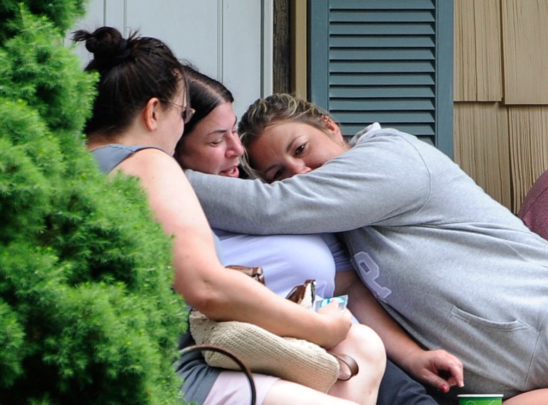 Kerry Gottlieb, center, owner of the home where a small airplane crashed in her backyard that killed the pilot is hugged by friend, Jill Cherveny, right on Tuesday, June 17, 2014, in East Patchogue, N.Y. The plane crashed  in between two houses on the tree-lined working-class street, according to Brookhaven Town spokesman Kevin Molloy.  The Federal Aviation Administration said the aircraft was a single-engine Lancair Columbia with one person was on board. It was flying from Republic Airport in Farmingdale to MacArthur Airport in Islip, the agency said. (AP Photo/Kathy Kmonicek)