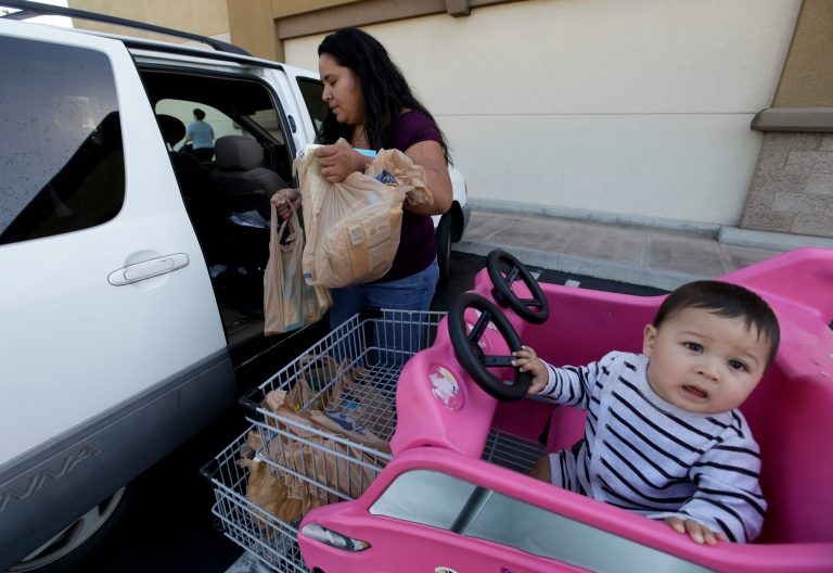 Irma Salazar, left, of Santa Ana, Calif., loads plastic grocery bags into her car as her son Miguel looks on, Tuesday, Sept. 30, 2014 in Santa Ana, Calif. Gov. Jerry Brown has signed legislation on Tuesday imposing the nation's first statewide ban on single-use plastic bags.(AP Photo/Chris Carlson)