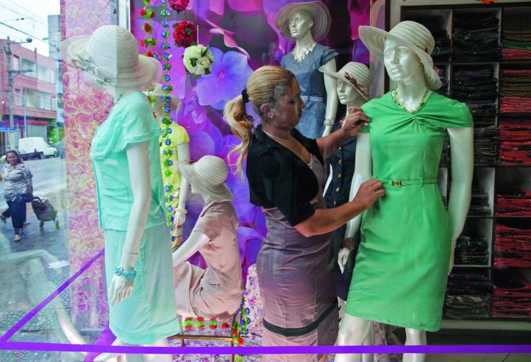 In this photo taken Sept. 21, 2012, a saleswoman adjusts a mannequin wearing a dress by the Brazilian brand Kauly, which markets itself as 