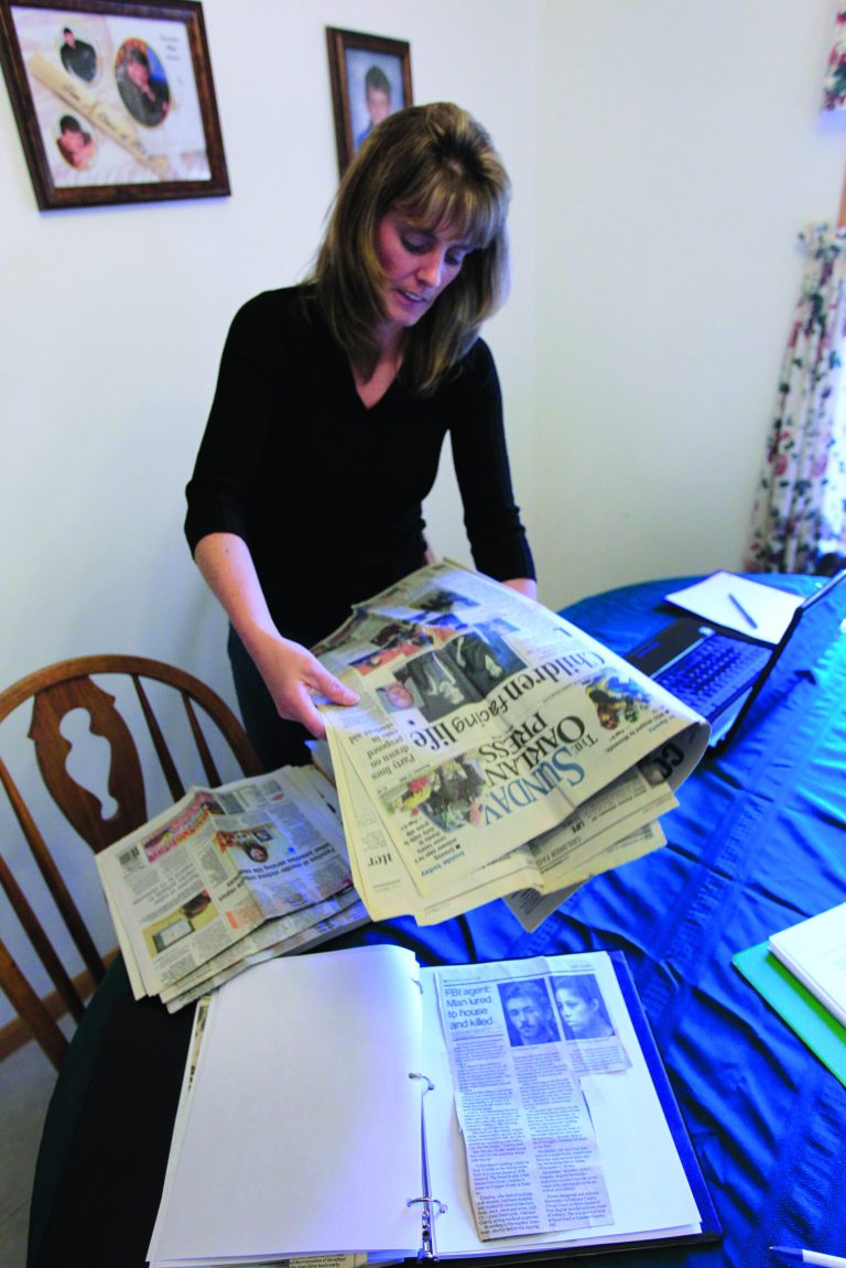 In this Oct. 17, 2012 photo, Jody Robinson, the younger sister of James Cotaling, who was murdered in 1990, looks through newspaper clippings about him at her home in Davisburg, Mich. On a Sunday morning eight Novembers ago, Robinson picked up a local newspaper topped by the headline, 