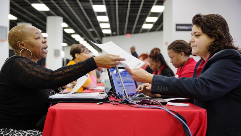 A homeowner hands paperwork to a bank associate in an attempt to lower her monthly mortgage payment. U.S. household debt has finally hit a new all-time high. (AP Photo/David Goldman, File)