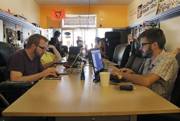 People work on computers at a communal workbench at HeatSync Labs in Phoenix, in this photo made Wednesday, July 23, 2014. The nondescript garage-like workshop nestled between restaurants, a flower shop and jewelry stores offers a space where inventors and tinkerers can work on projects and share ideas. (AP Photo/Emaun Kashfi)