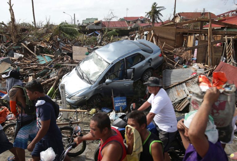 Survivors move past the damages caused by Typhoon Haiyan in Tacloban city, Leyte province central Philippines on Monday, Nov. 11, 2013. Authorities said at least 2 million people in 41 provinces had been affected by Friday's disaster and at least 23,000 houses had been damaged or destroyed. (AP Photo/Aaron Favila)