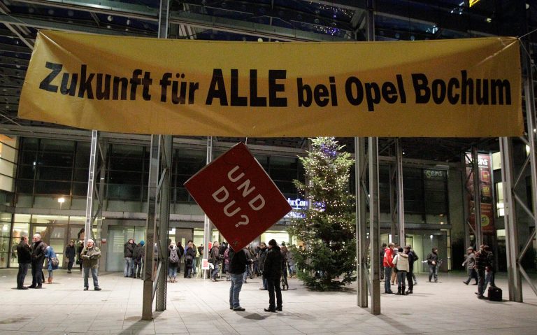   Opel employees queue for a staff meeting in Bochum, Germany, Monday, Dec. 10, 2012. The poster reads:' Future for all at Opel Bochum' with sign hanging under reading 