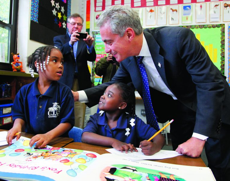 FILE - In this Oct. 27, 2011 file photo, Chicago Mayor Rahm Emanuel, right, visits with Brandy Toliver, left, and Mariah Neyland, in their first-grade class at the CICS Washington Park School on Chicago's South Side. The Chicago Public Schools extended the school day from 5 hours and 45 minutes to 7 hours in 2012 after a heated offensive by parents. Emanuel, a proponent of longer school days, had originally proposed a 7 1/2-hour school stay, but adjusted his proposal after discussions with parents, some of whom had been critical of the original plan. (AP Photo/Charles Rex Arbogast, File)