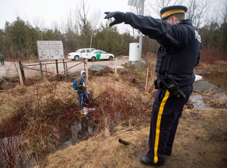 An RCMP officer warns a man to cross at the legal border crossing or he will be arrested at the border from New York into Canada on Wednesday, March 8, 2017 in Hemmingford, Quebec. America's neighbor to the north has been increasingly seen as a haven for some immigrants who are willing to chance a walk across the border in sometimes dangerous cold to get there. (Ryan Remiorz/The Canadian Press via AP)