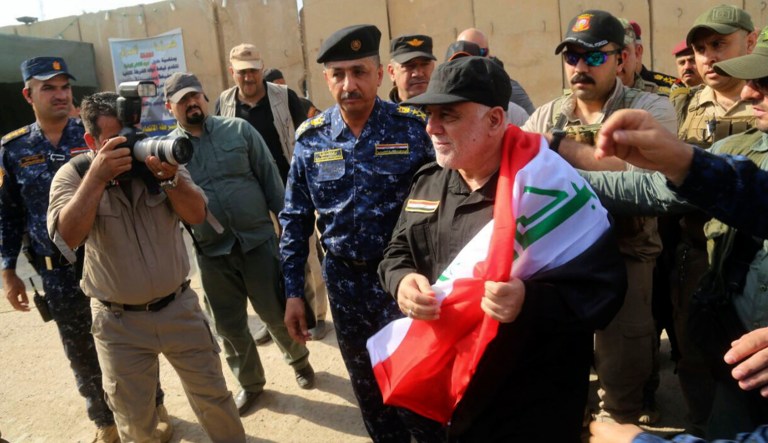Iraq's Prime Minister Haider Al-Abadi, center, holds a national flag upon his arrival to Mosul, Iraq, Sunday, July 9, 2017. (Iraqi Federal Police Press Office via AP)