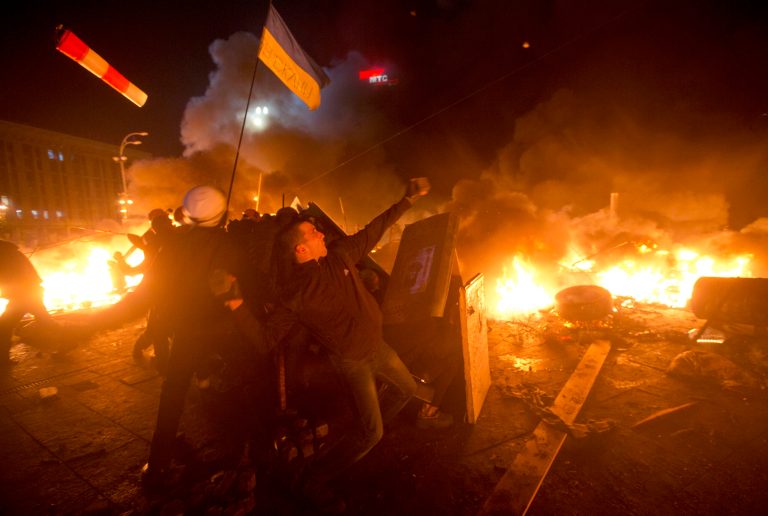 Anti-government protesters clash with riot police in Kiev's Independence Square, the epicenter of the country's current unrest, Kiev, Ukraine, Tuesday, Feb. 18, 2014. Thousands of police armed with stun grenades and water cannons attacked a large opposition camp in Ukraine's capital on Tuesday that has been the center of nearly three months of anti-government protests after at least nine people were killed in street clashes. (AP Photo/Efrem Lukatsky)