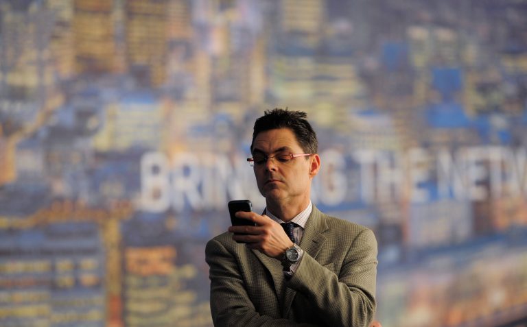 FILE - In this Wednesday, Feb. 27, 2013, file photo, a man checks his phone at the Mobile World Congress, the world's largest mobile phone trade show, in Barcelona, Spain. The U.S. wireless industry is in the midst of a shake-up, to stop subsidizing phones bought by its customers. That means customers can quickly get the new phones expected this week at the 2014 Mobile World Congress wireless show, which begins Monday, Feb. 24, 2014, in Barcelona, Spain. (AP Photo/Manu Fernandez, File)