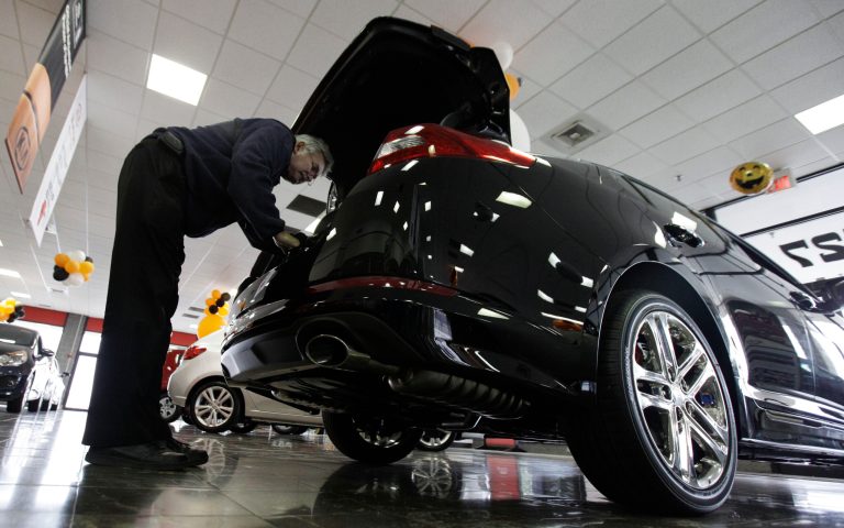FILE - In this Oct. 5, 2012 file photo, a shopper checks out a Kia Optima at a Kia car dealership in Elmhurst, Ill. Auto Web sites _ once filled mostly with reviews and advice _ are getting more sophisticated, connecting potential buyers with dealers and offering instant price guarantees. (AP Photo/Nam Y. Huh, File)