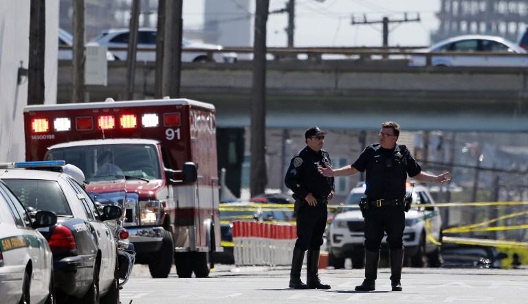 A San Francisco police officer gestures while standing outside a UPS package delivery warehouse where a shooting took place Wednesday, June 14, 2017, in San Francisco. A UPS spokesman says four people were injured in the shooting at the facility and that the shooter was an employee. (AP Photo/Eric Risberg)