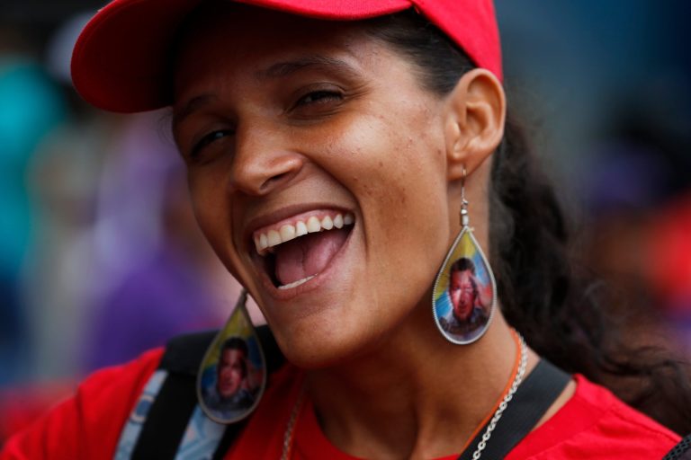 A woman wearing earrings designed with an image of the late President Hugo Chavez, smiles during a pro-government rally in Caracas, Venezuela, Saturday, Feb. 22, 2014. Venezuelans on both sides of the nation's political divide took to the streets on Saturday after nearly two weeks of mass protests that have Venezuelan President Nicolas Maduro scrambling to reassert his leadership. (AP Photo/Fernando Llano)