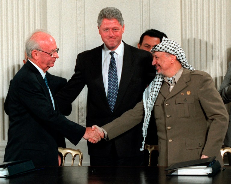 This Sept. 28, 1995 file photo shows President Bill Clinton gesturing toward Israeli Prime Minister Yitzhak Rabin, left, and PLO leader Yasser Arafat shaking hands in the East Room of the White House after the Mideast accord signing.