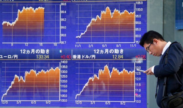 A man checks cell-phone in front of an electronic stock board of a securities firm in Tokyo, Tuesday, Nov. 12, 2013. Asian stock markets mostly traded higher Tuesday after the Dow Jones industrial average hit another all-time high. Tokyo's Nikkei jumped 1.9 percent to 14,534.91. (AP Photo/Koji Sasahara)