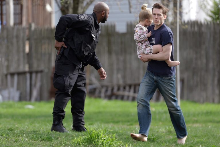 A police officer evacuates a shoeless man holding a child as members of law enforcement conduct a search for a suspect in the Boston Marathon bombings, Friday, April 19, 2013, in Watertown, Mass. The two suspects in the Boston Marathon bombing killed an MIT police officer and hurled explosives at police in a car chase and gun battle overnight that left one of them dead and his brother on the loose, authorities said Friday as thousands of officers swarmed the streets in a manhunt that all but paralyzed the Boston area. (AP Photo/Matt Rourke)