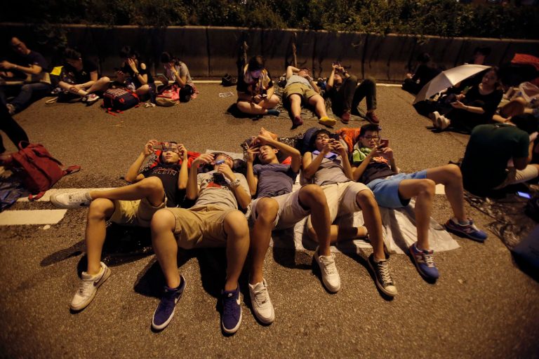 Student protesters rest as thousands occupy a main thoroughfare in Hong Kong, late Tuesday, Sept. 30, 2014. Hong Kong's leader refused to meet with pro-democracy demonstrators by their midnight deadline Tuesday, despite their threats to expand the protests that have clogged the streets with tens of thousands of people in the stiffest challenge to Beijing's authority since China took control of the former British colony in 1997. (AP Photo/Wally Santana)