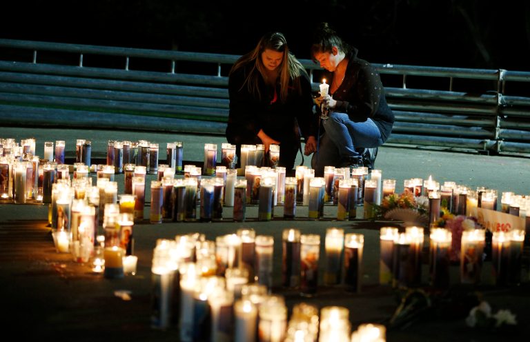 Meriah Calvert, left, of Roseburg, Ore., and an unidentified woman pray by candles spelling out the initials for Umpqua Community College after a candlelight vigil Thursday, Oct. 1, 2015, in Roseburg, Ore. (AP Photo/John Locher)