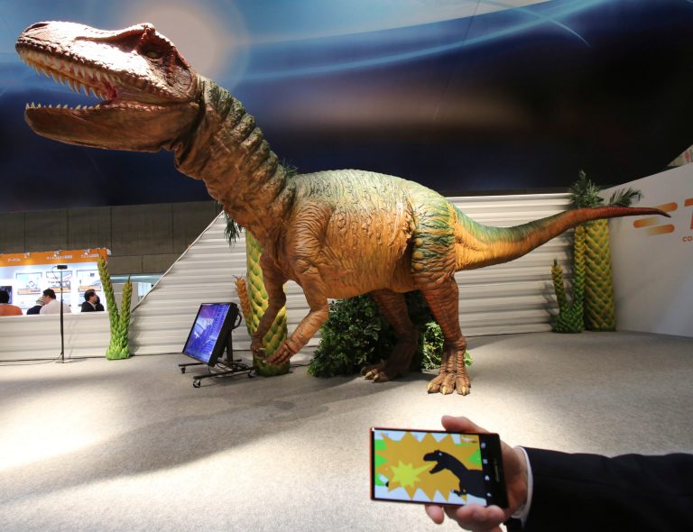 A TE Connectivity Japan staff member demonstrates how to control remotely its dinosaur robot 