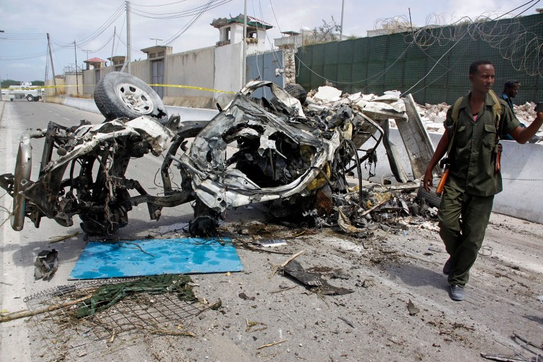 A Somali soldier stands near the wreckage of a car bomb outside the UN's office in Mogadishu, Somalia. (AP Photo/Farah Abdi Warsameh)