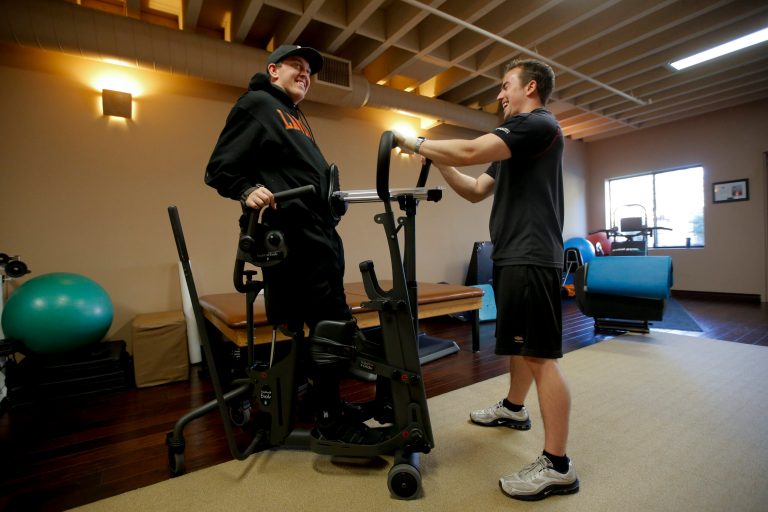 Hal Hargrave Jr., left, who is paralyzed from the neck down after a car crash when he was 17, shares a laugh with his trainer Chris Fitzgerald during his physical therapy session at a gym in Claremont, Calif., Wednesday, Dec. 19, 2012. After years of grueling physical therapy, Hargrave started the nonprofit Be Perfect Foundation and raised $2 million to help other young people who couldn't afford the same kind of rehabilitation program made available to him. (AP Photo/Jae C. Hong)