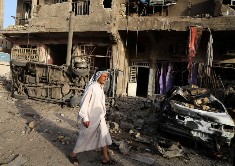 A man walks near the site of double car bombings in the northern Shiite district of al-Hurriyah in Baghdad, Iraq, Wednesday, Oct. 1, 2014. On Tuesday, officials said a wave of bombings targeted commercial areas across Iraq, killing and wounding dozens of people. (AP Photo/Karim Kadim)