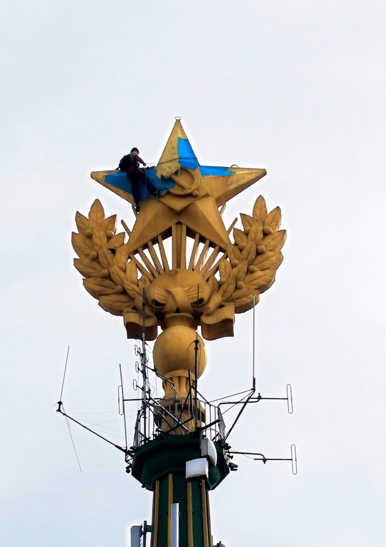 A worker paints  yellow over the blue at one of Moscow's Stalin-era skyscraper with a star on top, which was painted in colors of Ukrainian national flag in Moscow, Russia, Wednesday, Aug. 20, 2014.   (AP Photo/Ivan Sekretarev)