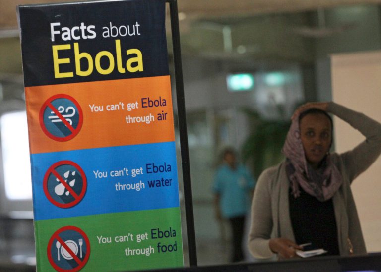 A tourist from Ethiopia walks behind a poster referring to Ebola, at Suvarnbhumi Airport in Bangkok, Thailand on Monday. (AP/Sakchai Lalit)