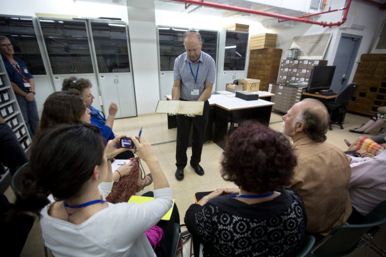 In this Monday, Sept. 8, 2014 photo, Yad Vashem's archive director Haim Gertner show's a document to visiting international experts and others who are participating in a workshop devoted to the physical and digital preservation of documents, in Jerusalem. With Holocaust survivors dying in growing numbers and their live testimonies soon to be a thing of the past, Holocaust commemoration efforts are increasingly focusing around preserving the belongings that contain their stories.  (AP Photo/Sebastian Scheiner)
