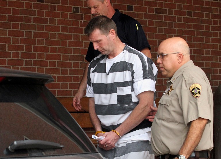 Curtis Lovelace is escorted out of the Adams County Courthouse in Quincy, Ill., Thursday, Aug. 28, 2014, after being formally charged with first-degree murder in the February 2006 death of his wife. Lovelace, a former assistant state's attorney in western Illinois' Adams County, is accused of suffocating Cory D. Lovelace. He was arrested Wednesday near his Quincy law office. (AP Photo/The Quincy Herald-Whig, Steve Bohnstedt)