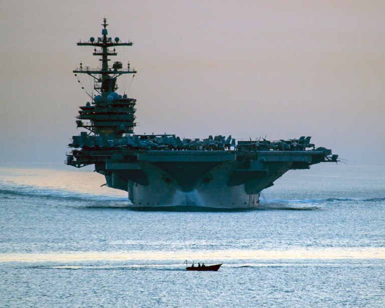 This image provided by the U.S. Navy shows a small vessel transiting in front of the aircraft carrier USS George H.W. Bush as it transits the Strait of Hormuz April 28, 2014 as seen from the guided-missile cruiser USS Philippine Sea. Defense Secretary Chuck Hagel ordered the USS George H.W. Bush from the northern Arabian Sea Saturday June 14, 2014 as President Barack Obama considered possible military options for Iraq. (AP Photo/US Navy, Specialist 3rd Class Abe McNatt)