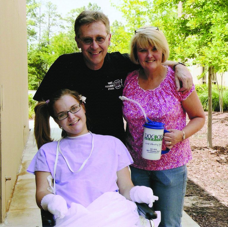 FILE - In this Saturday, June 23 2012 file photo provided by the Copeland family, Aimee Copeland, left, poses with her parents, Andy and Donna Copeland, outside Doctors Hospital in Augusta, Ga. Aimee Copeland was released from Doctors Hospital on Monday, July 2, 2012. She will move to an inpatient rehabilitation clinic and spend the next several weeks learning to move herself with the aid of a wheelchair after having her left leg, right foot and both hands amputated. (AP Photo/Copeland Family, File)