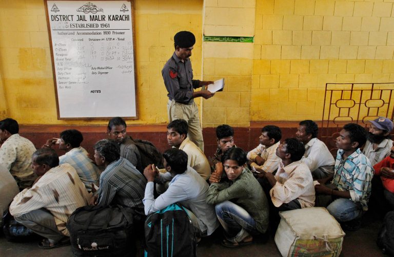 A Pakistani police officer checks the documents of an Indian fishermen waiting for their release from a prison in Karachi, Pakistan, Sunday, May 25, 2014. Pakistan released over 150 Indian fishermen who were arrested on the charges of illegally entering Pakistan's territorial waters, ahead of Pakistani Prime Minister Nawaz Sharif's trip to Delhi to attend the inauguration ceremony of India's newly elected prime minister, Narendra Modi. (AP Photo/Fareed Khan)