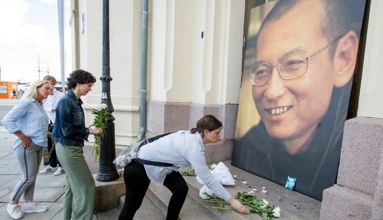 Officials say China's most prominent political prisoner, Nobel Peace Prize laureate Liu Xiaobo, has died. He was 61. People place flowers and light candles in front of a picture of Liu Xiaobo. (Audun Braastad/NTB scanpix via AP)