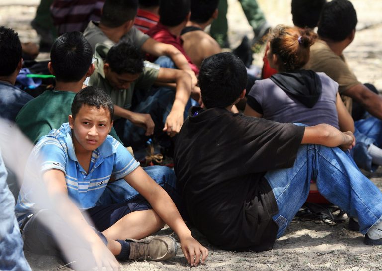 People wait under a tree after they were detained by Border Patrol agents Tuesday June 25, 2013 at a field in Edinburg, Texas. Agents took into custody 69 people suspected of entering the country illegally. (AP Photo/The Monitor, Gabe Hernandez)  MAGS OUT; TV OUT