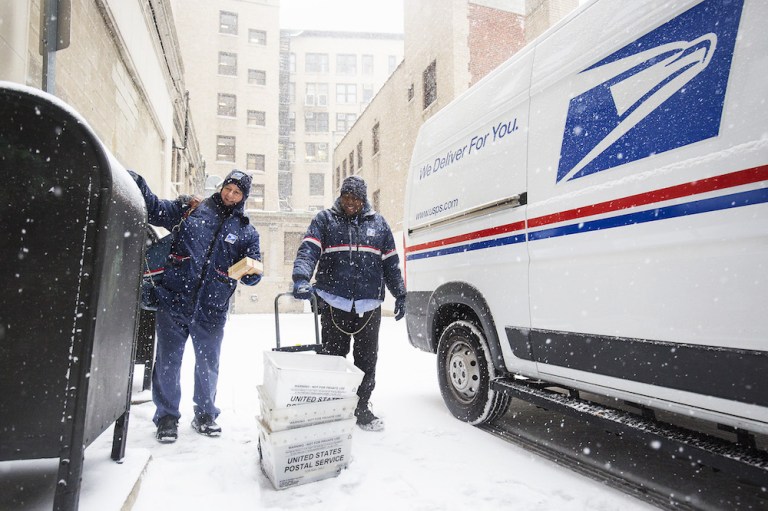 U.S. Postal Service letter carriers deliver mail during a snow storm in Boston in January. The organization posted a loss in the last three months of 2017, a period that's typically its busiest due to mailing of Christmas cards and presents. (Adam Glanzman/Bloomberg)