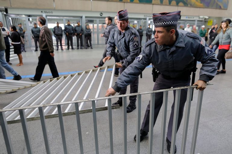 Police pick up barriers at the entry of the Corinthians Itaquera metro station after they were kicked down by commuters protesting the metro strike in Sao Paulo, Brazil, Thursday, June 5, 2014. This city that will host the World Cup opening match in a week was thrown into transit chaos Thursday as subway and overland commuter train operators went on strike, putting at risk the only means that most soccer fans will have to reach the stadium. (AP Photo/Nelson Antoine)