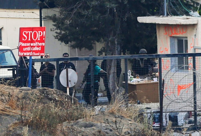 An armed group of men, not specified which group of rebels, gather at Syria's Quneitra border crossing between Syria and the Israeli-controlled Golan Heights, Friday, Aug. 29, 2014. It was unclear if the men were connected to an armed group that, the United Nations said, detained more than 40 U.N. peacekeepers during fighting in Syria early Thursday. The peacekeepers were detained on the Syrian side of the Golan Heights during a 