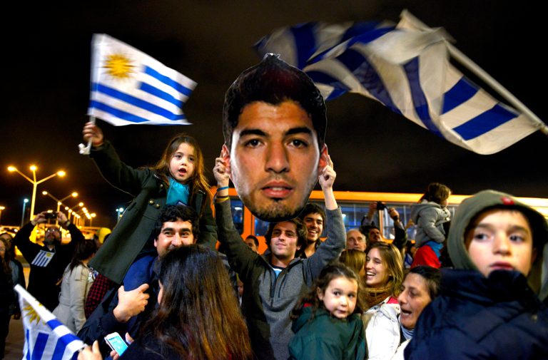 Fans of Uruguay's national soccer team await the arrival of Uruguay player Luis Suarez at Carrasco International Airport in the outskirts of Montevideo, Uruguay, Thursday, June 26, 2014. The Uruguay forward, widely regarded as one of the best players in the world, was banned by FIFA from all football for four months on Thursday for biting an Italian opponent in an incident that marred the team's victory and progression to the second round. (AP Photo/Matilde Campodonico)