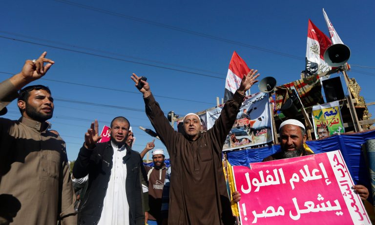   Islamist protesters supporting Egyptian President Mohammed Morsi chant slogans in front of the Media City complex in Giza, Egypt, Wednesday, Dec. 12, 2012. The Arabic sign at right reads, 