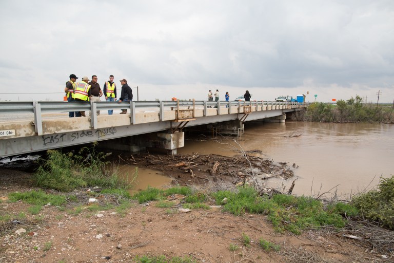Members of the Pecos fire department, with officials from numbering counties and Federal officials, inspect the rising water level on the Pecos River at the Barstow bridge in Ward County, Texas, Monday, Sept. 22, 2014. (AP Photo/The Odessa American, Courtney Sacco)