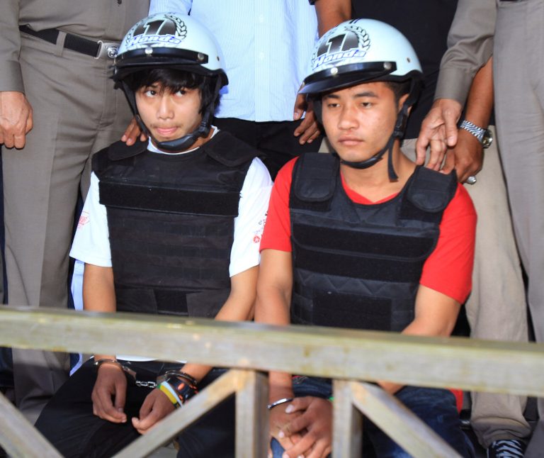 Workers from Myanmar, Saw, left, and Win, sit together, escorted by a Thai police officer, during a press conference in Koh Tao island, Surat Thani province. Thailand, Friday, Oct. 3, 2014.  Thai police have arrested the two Myanmar workers they say confessed to killing a pair of British tourists on a beach in the southern Thailand last month. (AP Photo) THAILAND OUT